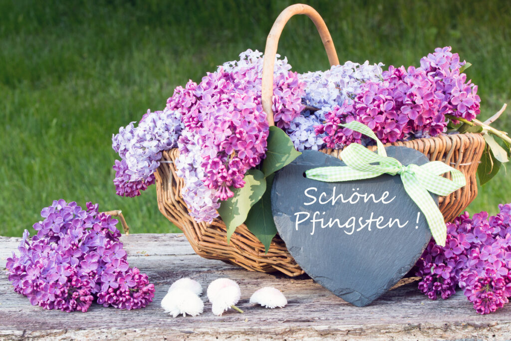 Pfingstenkorb mit lila Blüten und einer Tafel